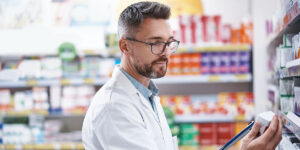 Farmacéutico, hombre y control de existencias con portapapeles para control de inventario, fecha de caducidad o información del producto. Trabajador, persona adulta e inspección de medicamentos con lista de verificación para precisión de etiquetas, medicamentos y venta al por menor.