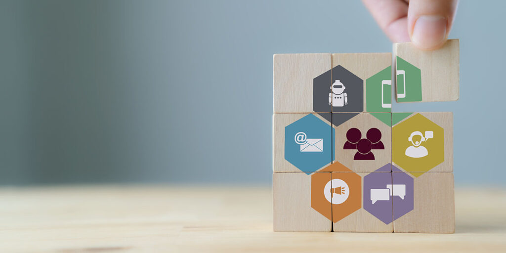 Concepto de fidelización del cliente. Tecnología, internet, negocios y marketing. Campaña de marketing y comunicación dirigida al cliente objetivo. Una mano coloca cubos de madera con canales online y offline para la fidelización.