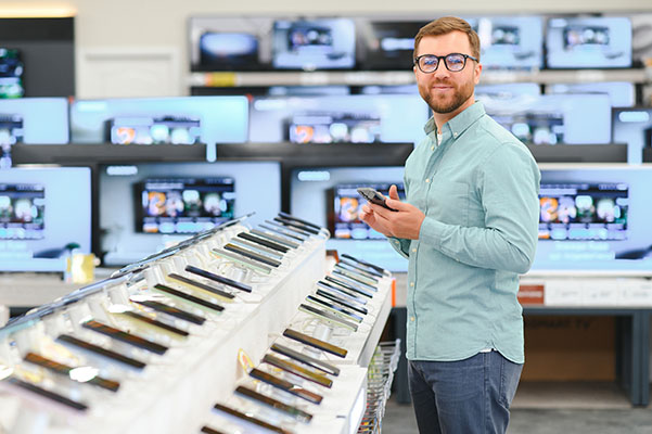 Joven feliz eligiendo un nuevo móvil en una tienda de tecnología.