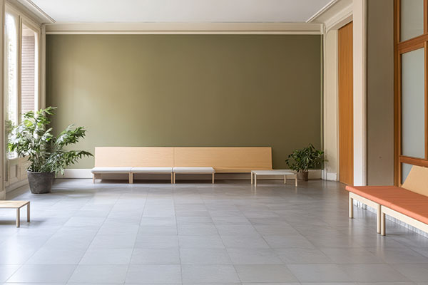 Una luminosa sala de espera cuenta con bancos minimalistas en colores neutros, grandes ventanales que permiten la entrada de luz natural y plantas en macetas que crean un ambiente tranquilo y acogedor para los visitantes.