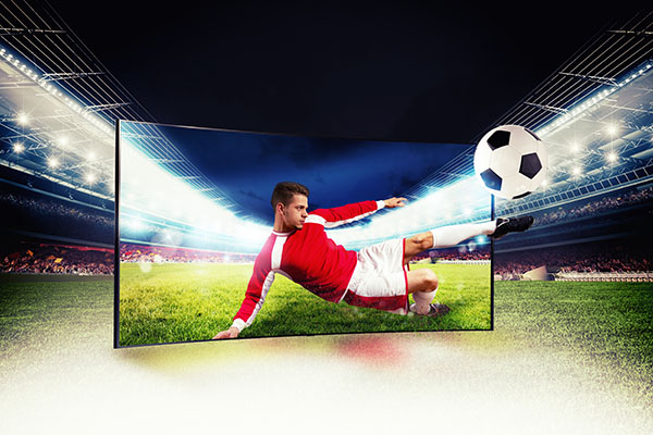 Jugador de fútbol sale del televisor para patear el balón.