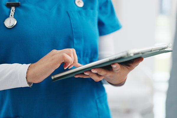 Mujer, enfermera y manos con tableta para chequeo médico, diagnóstico o investigación en el hospital. Primer plano: mujer o profesional de la salud navegando con tecnología para telesalud, redes o información.