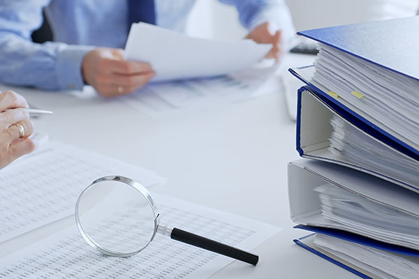 Los contadores analizan informes financieros con lupa y documentos, realizando tareas de contabilidad y auditoría en la oficina, de cerca. Auditoría e impuestos en los negocios.