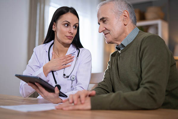 Médico hablando sobre información de salud con un paciente mayor.