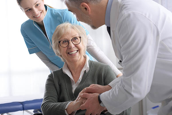 Médico y paciente mayor dándose la mano en el consultorio.