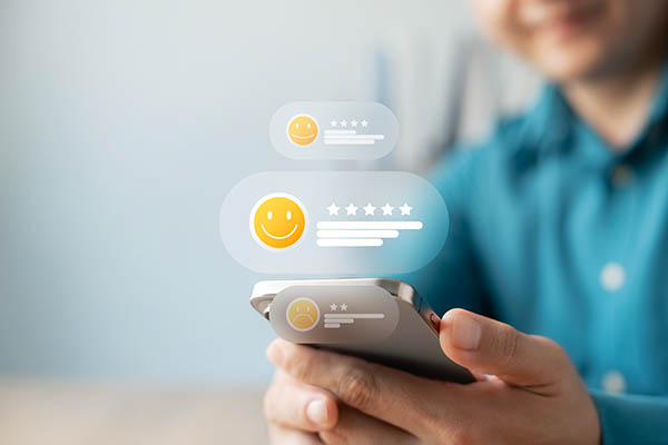 Clientes satisfechos que dejan comentarios positivos en sus teléfonos móviles con una calificación de cinco estrellas y un emoji sonriente. Concepto de experiencia de usuario, sistema de reseñas en línea, productos y servicios excelentes.