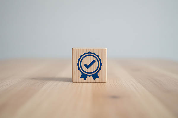 Un bloque de madera con una marca de verificación azul y una cinta sobre una mesa.