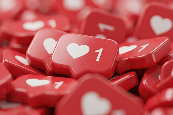 Primer plano de numerosos iconos rojos de notificación de redes sociales con corazones blancos y el número uno, que simbolizan los "me gusta" y la interacción.