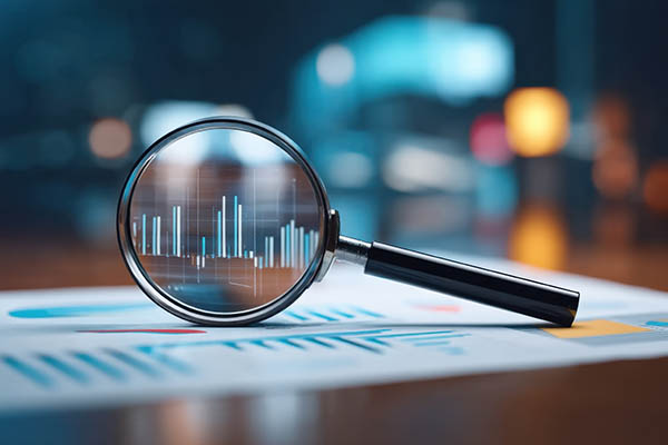 Examinando gráficos empresariales y análisis de datos con lupa en un entorno de oficina especializado.